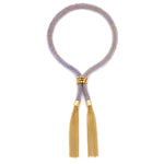 A lilac and gold tassel bracelet with a woven fabric and a ball clasp, featuring gold 18ct gold vermeil chain.