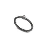 A black rhodium plated sterling silver ring with a twisted motif and a natural white zircon in the centre, designed for stacking.