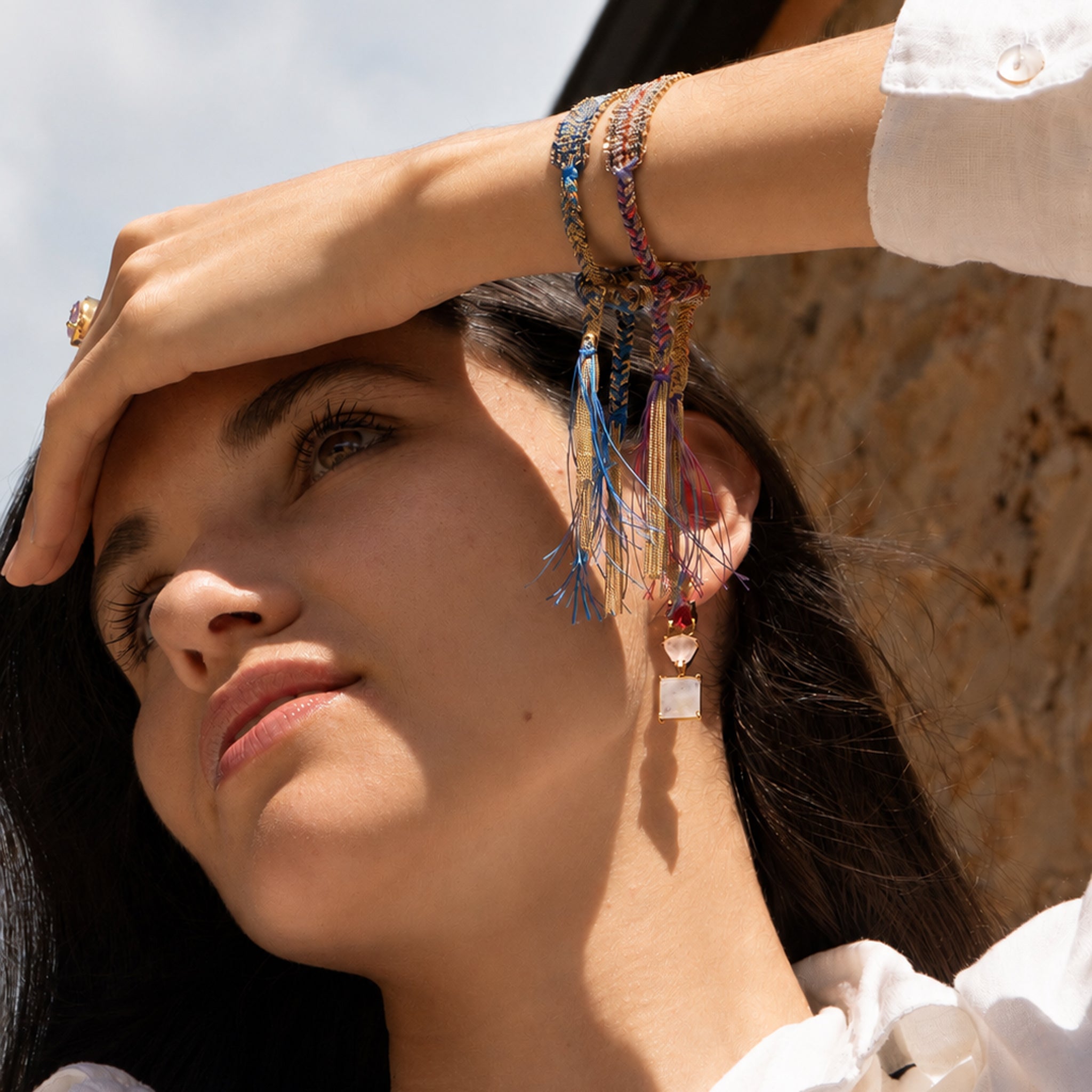 model wearing two colourful ASSYA woven tie friendship bracelets and gemstone earrings